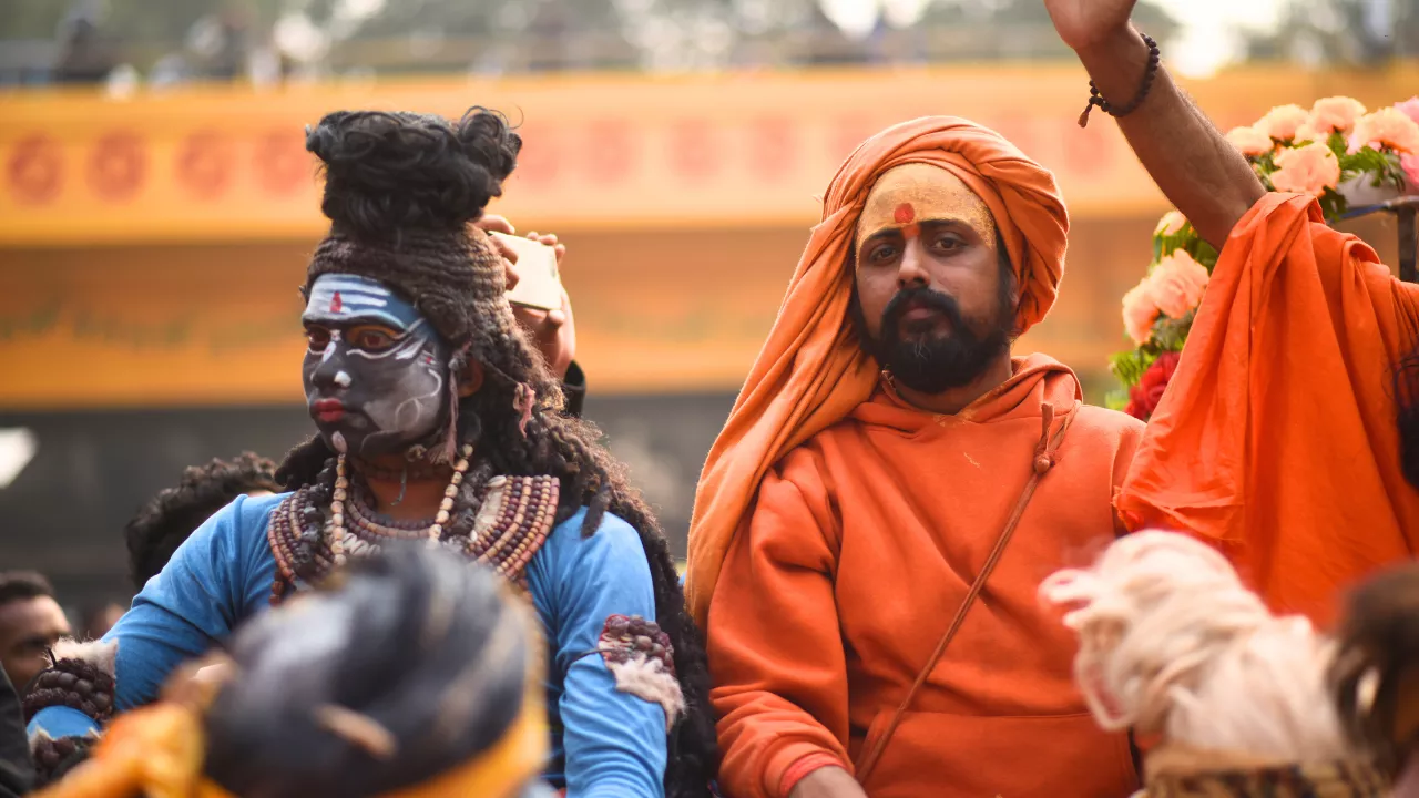 An older pilgrim being assisted during a ceremony at the Magh Mela